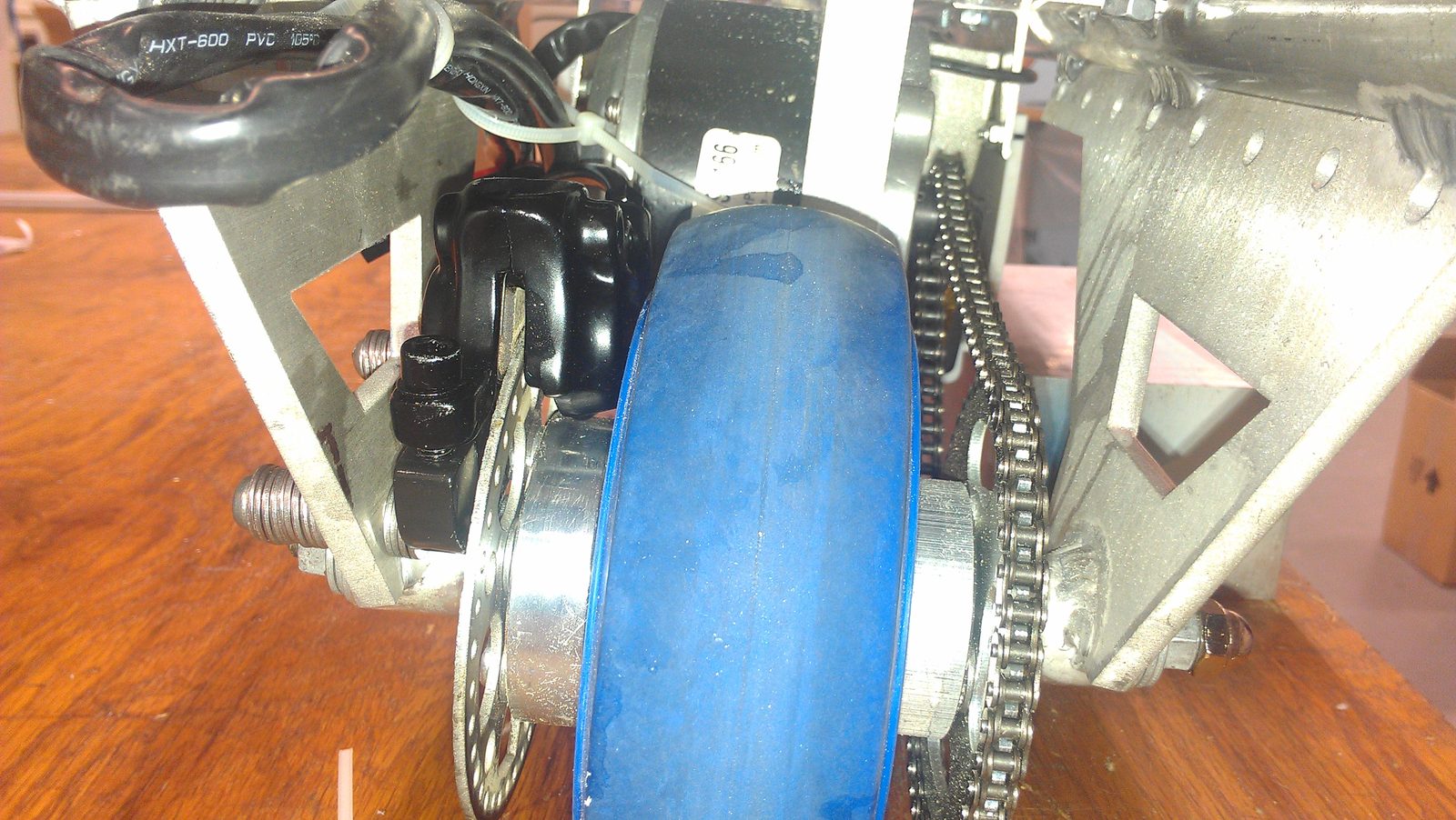 Rear wheel assembly — chain drive from the brushless motor, disc brake, and the welded aluminum swingarm