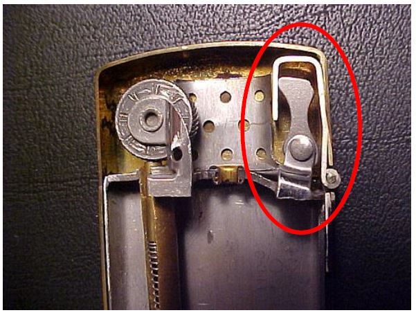 Close-up photograph of the inside of the lighter case with the cam and spring plate mechanism circled in red beside the flint wheel