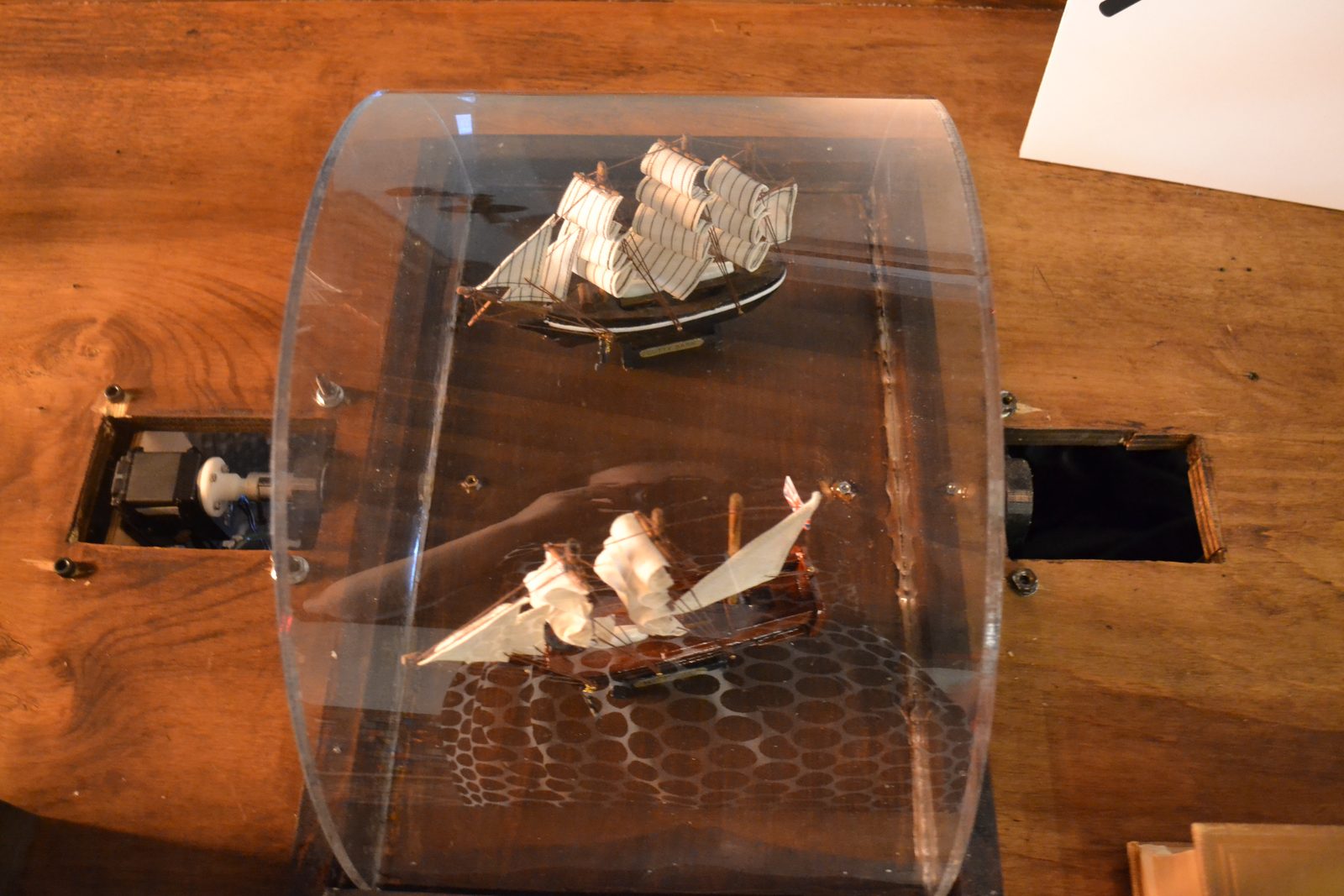 The rotating section carrying a pair of model ships under an acrylic cover, with the drive visible through the cutouts on either side