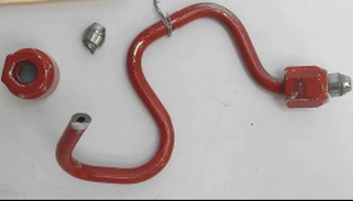 A high-pressure fuel line fractured into two pieces, laid out beside its rail nut and a smaller fitting
