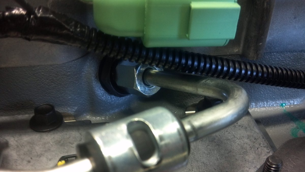 A high-pressure fuel line and its nut installed on an engine, photographed after torquing