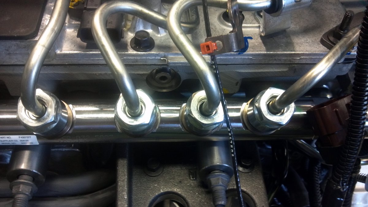 Several high-pressure fuel lines running from the rail to the injectors along the top of an engine