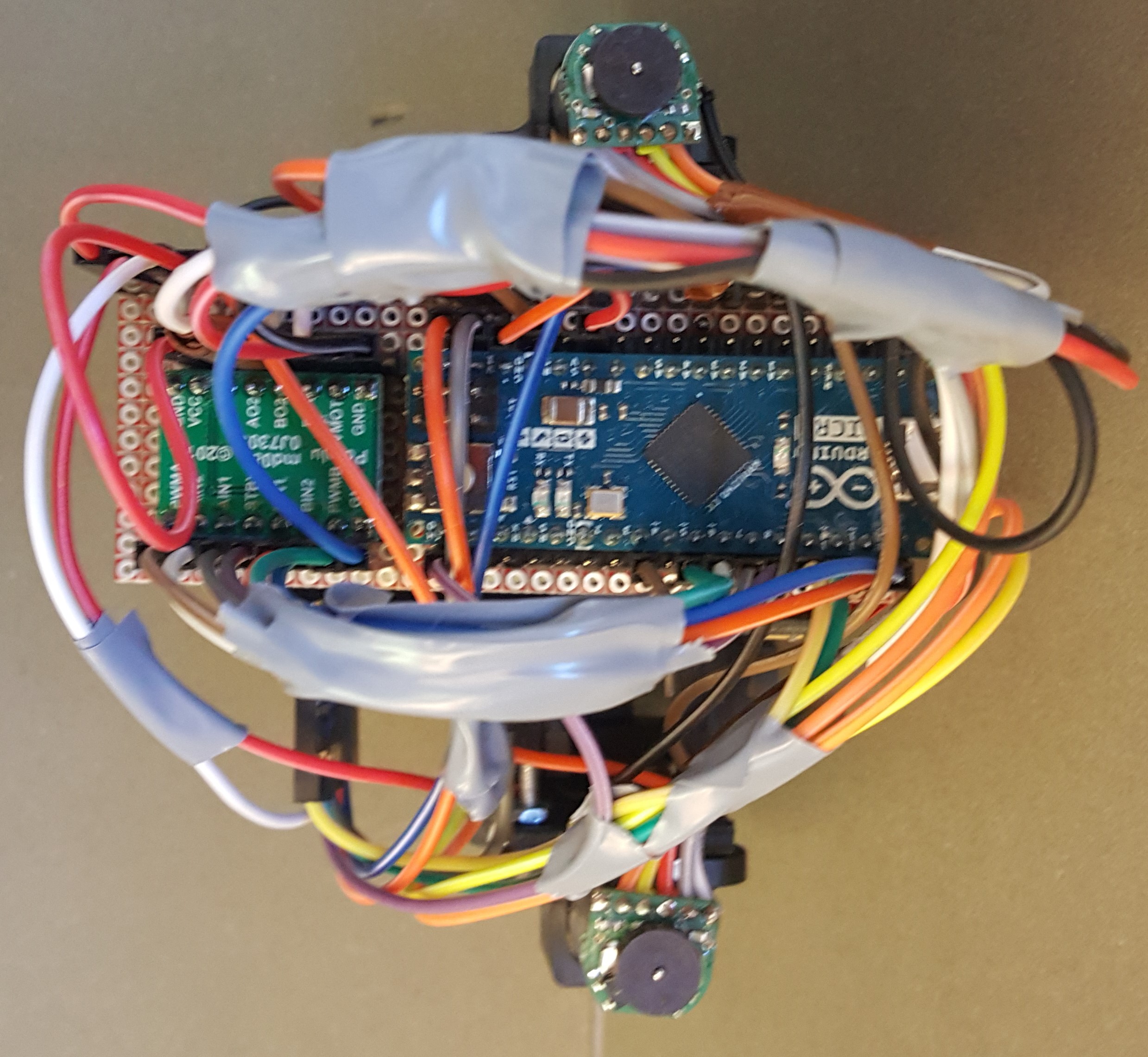 Close-up photograph of the carriage electronics -- an Arduino Micro and motor driver on protoboard, wrapped in a dense bundle of coloured wiring, with IR receiver boards top and bottom